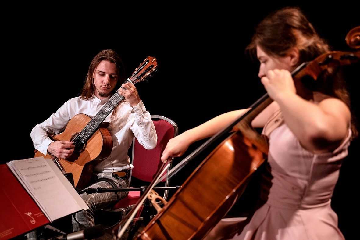 Guitarcello Duo, czyli wiolonczelista Karolina Kocyła w zwiewnej różowej sukni i gitarzysta Kamil Bućko (długie ciemne włosy, biała koszula) podczas koncertu na scenie Światowida