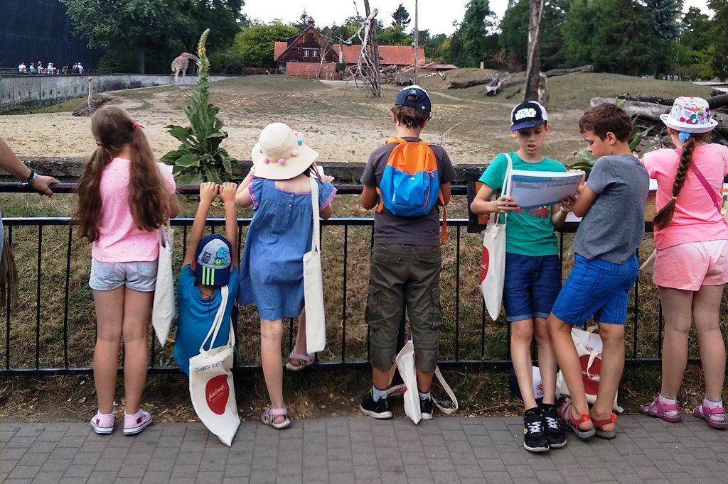 dzieci stoją przy wybiegu strusi w Zoo