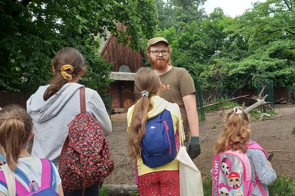 W zoo przy zagrodzie reniferów, opiekun opowiada grupie dzieci o zwierzętach